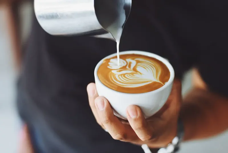 Barista menuang latte art ke dalam cangkir