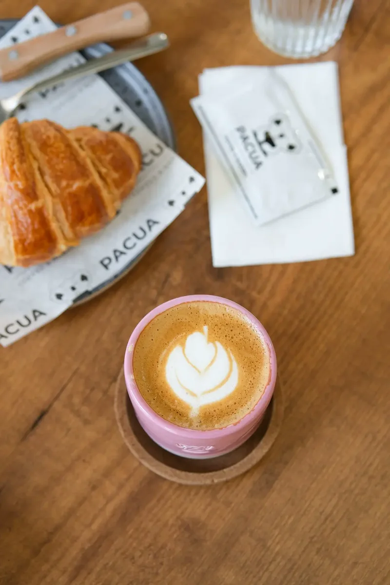 Latte art dan croissant di meja kayu