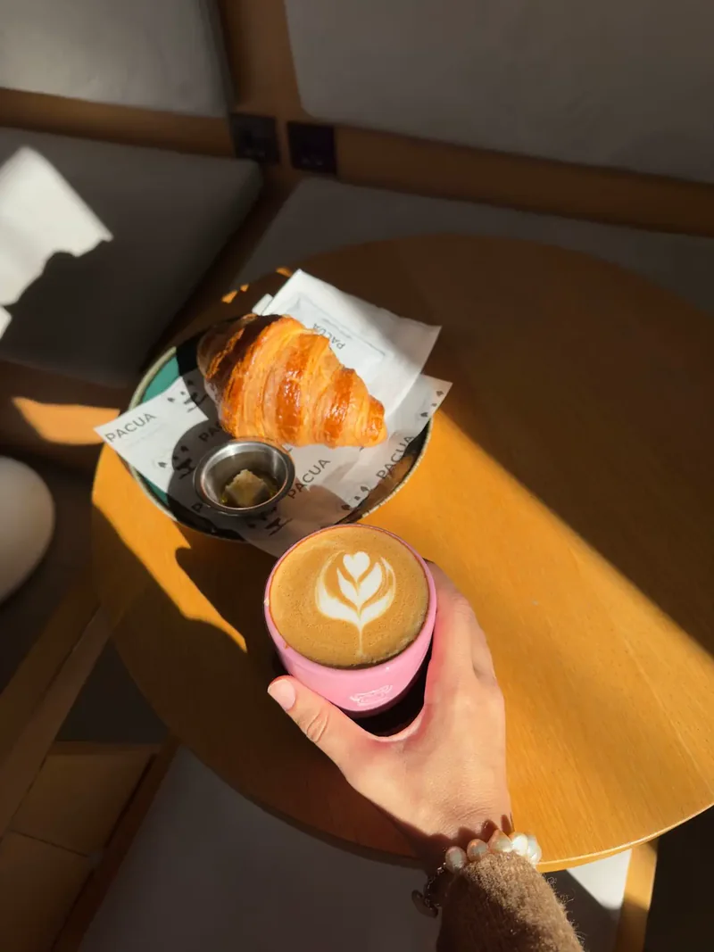 Latte dan croissant di meja kafe