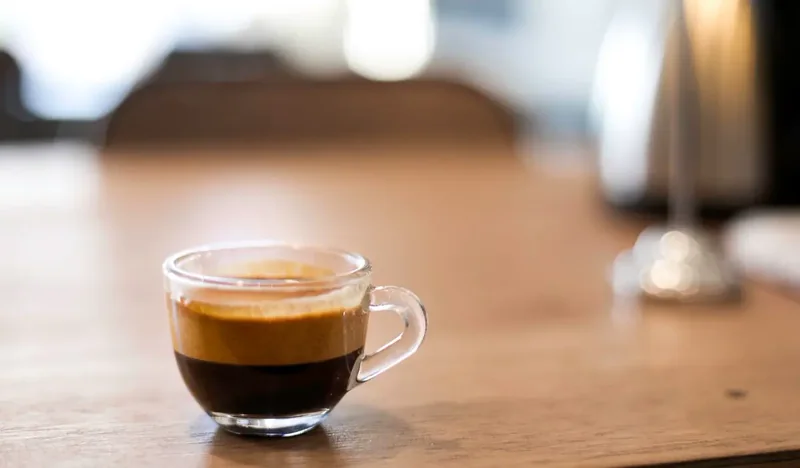 Kopi hitam di gelas di atas meja kayu