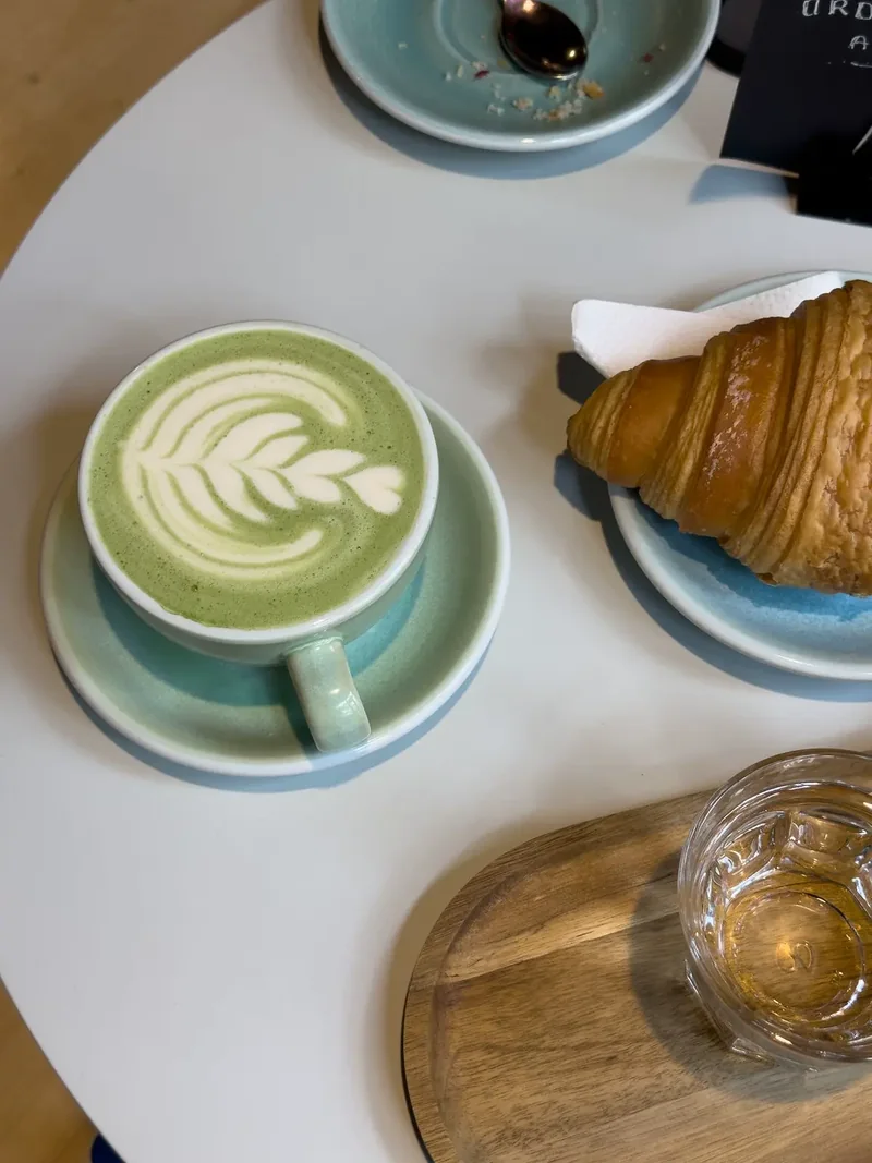 Matcha latte dan croissant di meja kafe