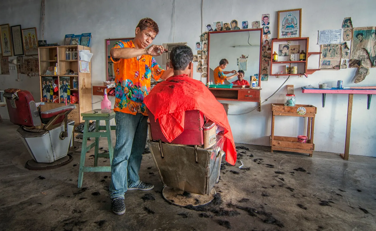 Tukang cukur sedang memotong rambut tamu