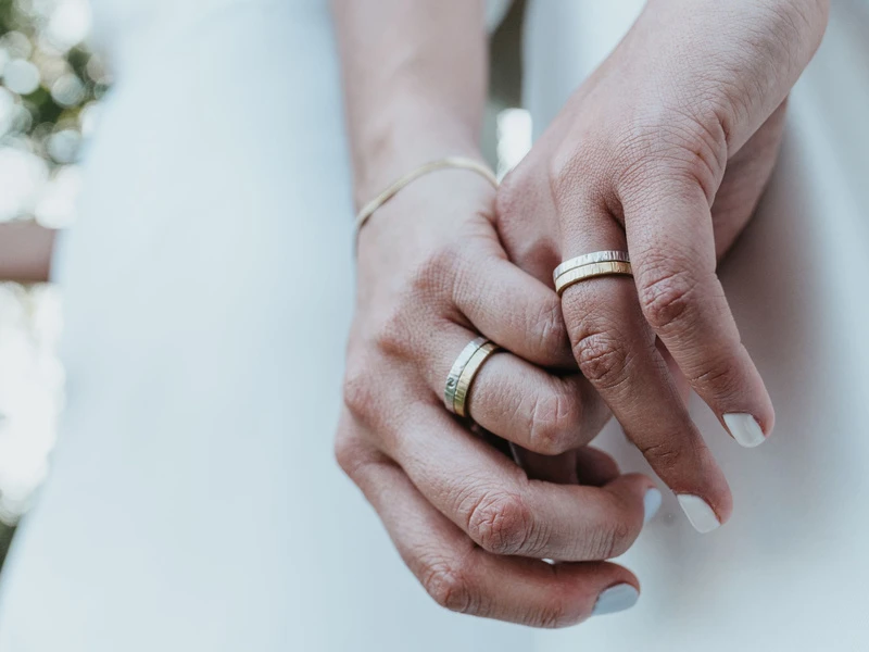 Dua tangan berpegangan, masing-masing memakai cincin
