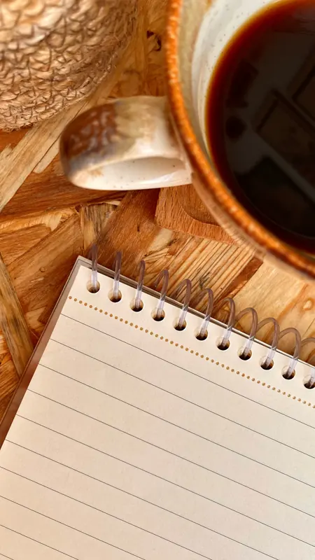 Cangkir dan buku catatan di meja kayu