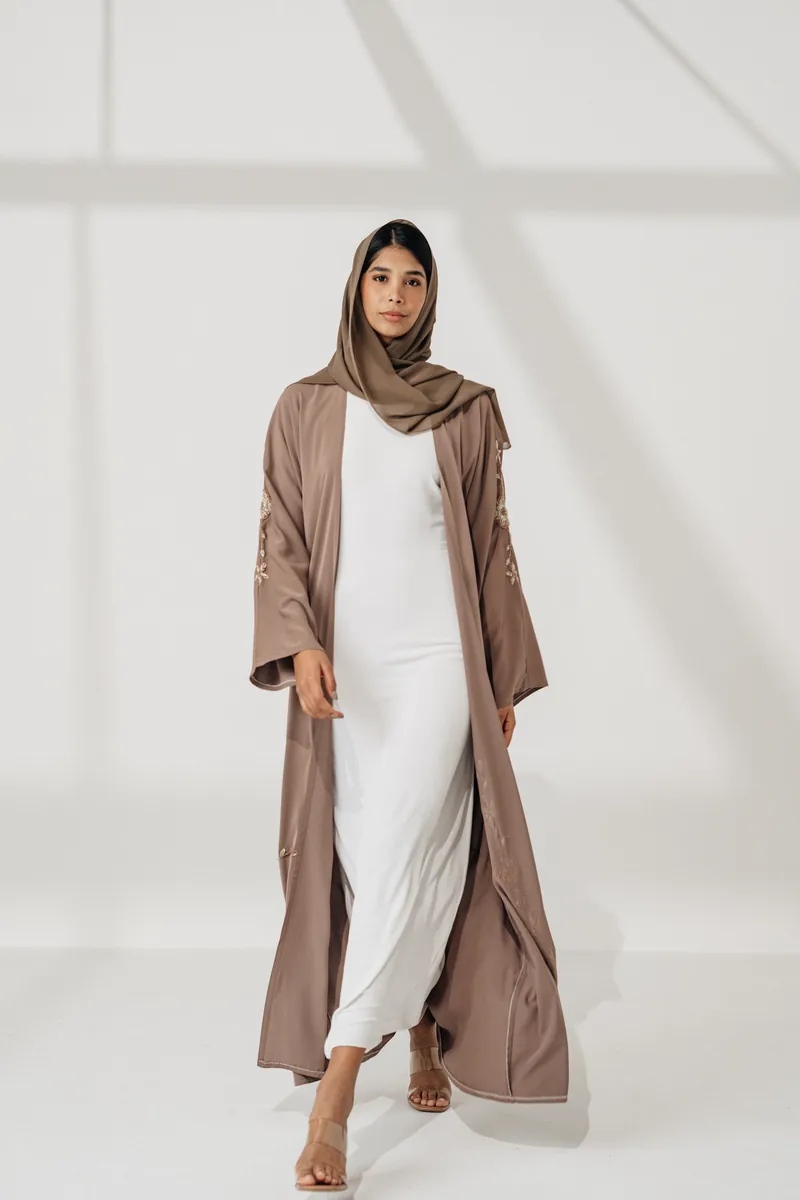 Model berhijab memakai abaya cokelat di studio