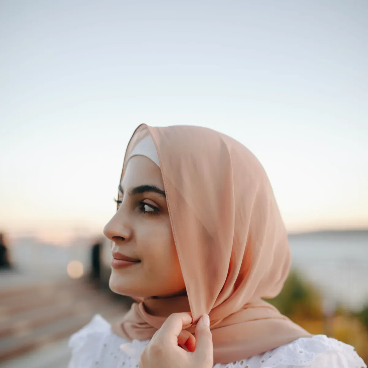 Model berhijab dan gaun putih di depan bangunan