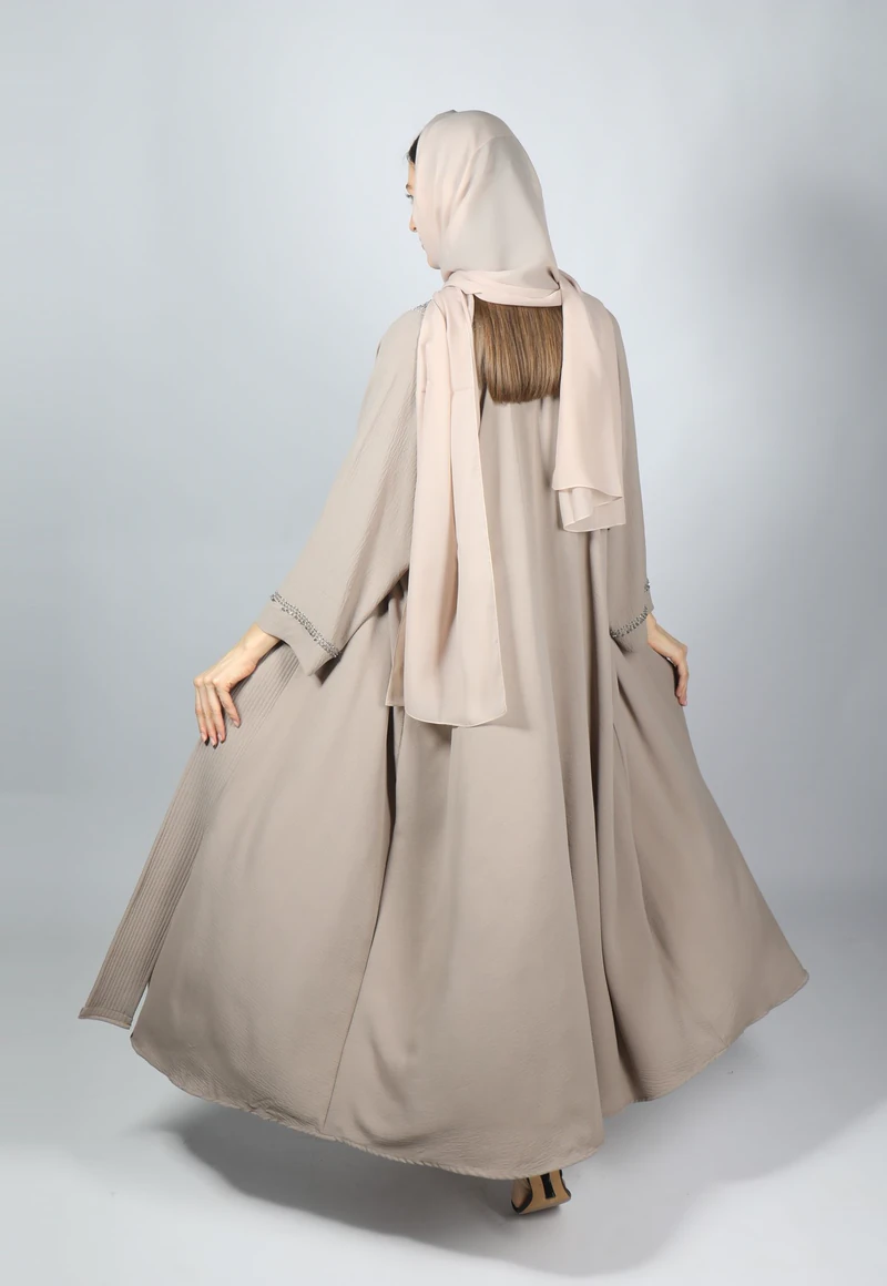 Model berhijab dari belakang memakai gamis krem panjang