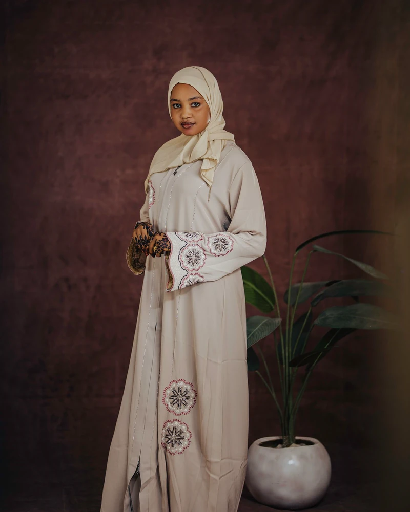 Model berhijab memakai gamis cokelat di dalam ruangan