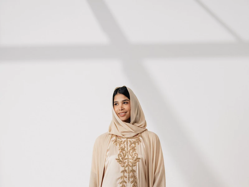 Model berhijab memakai gamis krem panjang di studio
