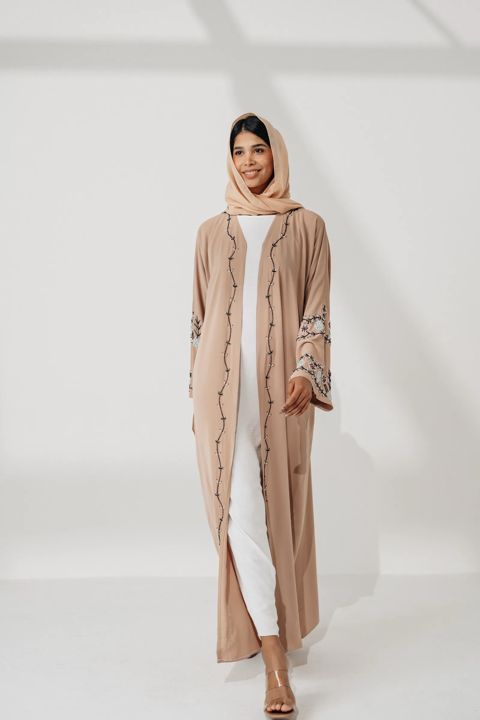 Model berhijab memakai abaya krem di studio