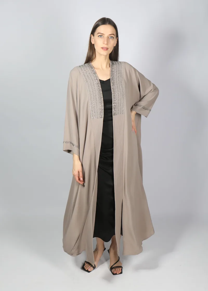 Model berhijab berdiri dengan abaya krem