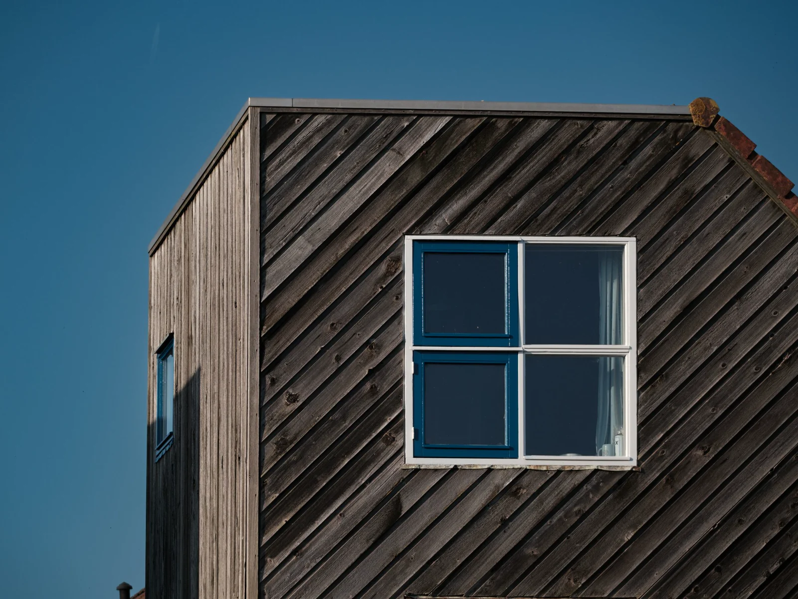 Rumah kayu dengan jendela biru di bawah langit cerah