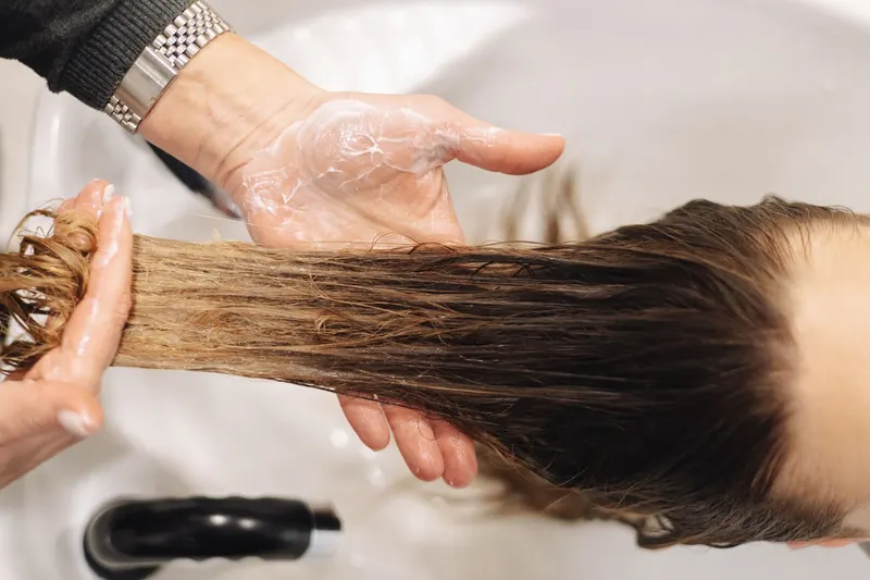 Tangan penata rambut saat mencuci rambut