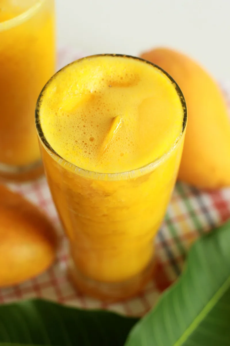 Smoothie mangga dalam gelas dengan potongan mangga