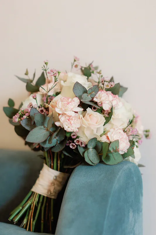 Buket mawar putih dengan daun hijau di kursi biru