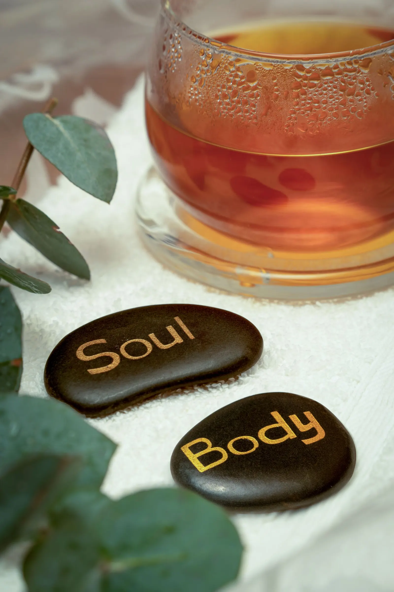 Batu spa, daun, dan teh di atas handuk