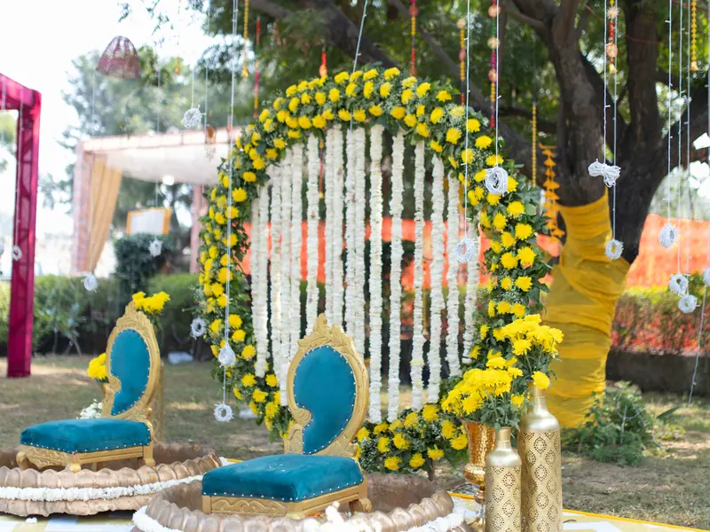 Dua kursi berlapis kain di depan lengkung bunga dan lampu